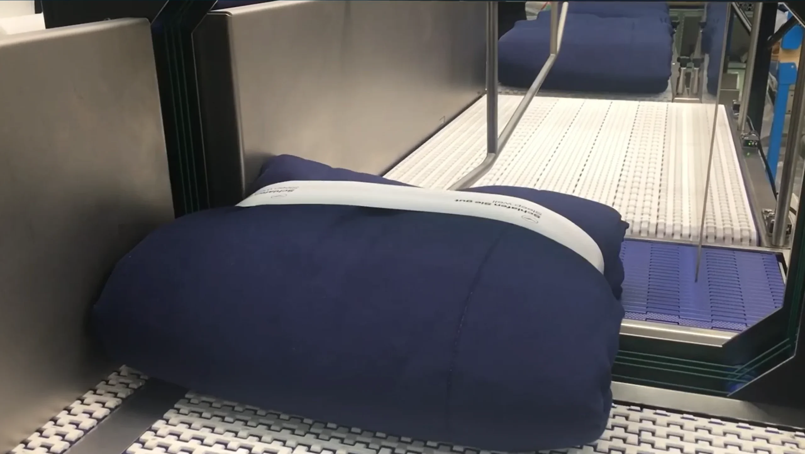 Airline laundry banding — banded blanket on the machine conveyor Filename: airline-laundry-banding-blanket-on-machine-conveyor