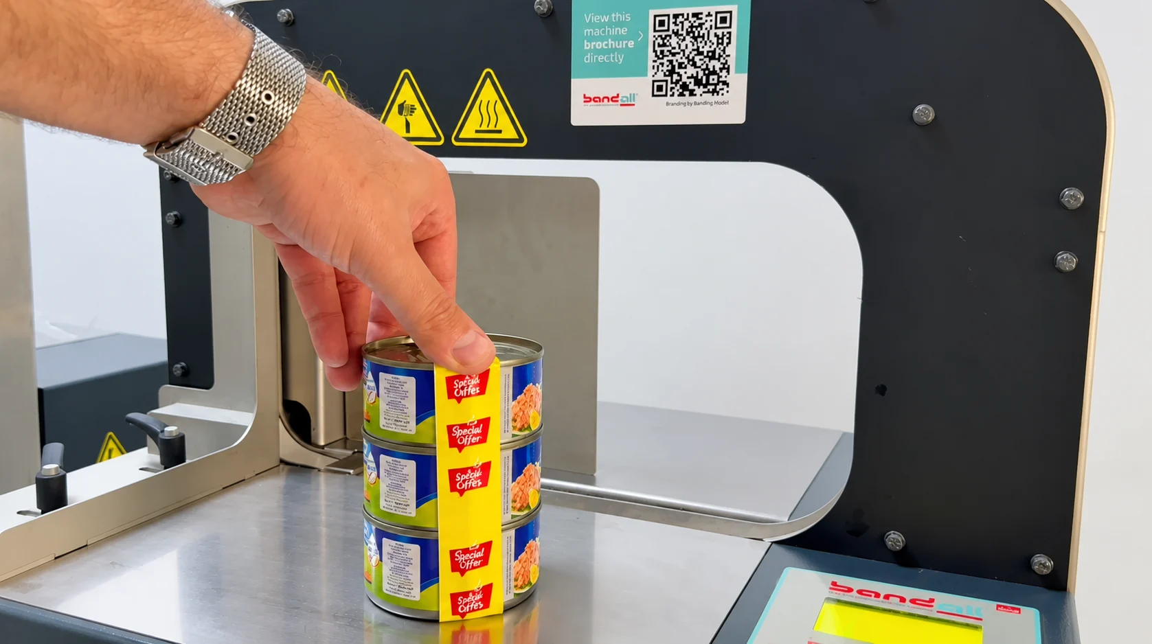 A stack of three tuna cans with a yellow printed band being applied on the Bandall machine