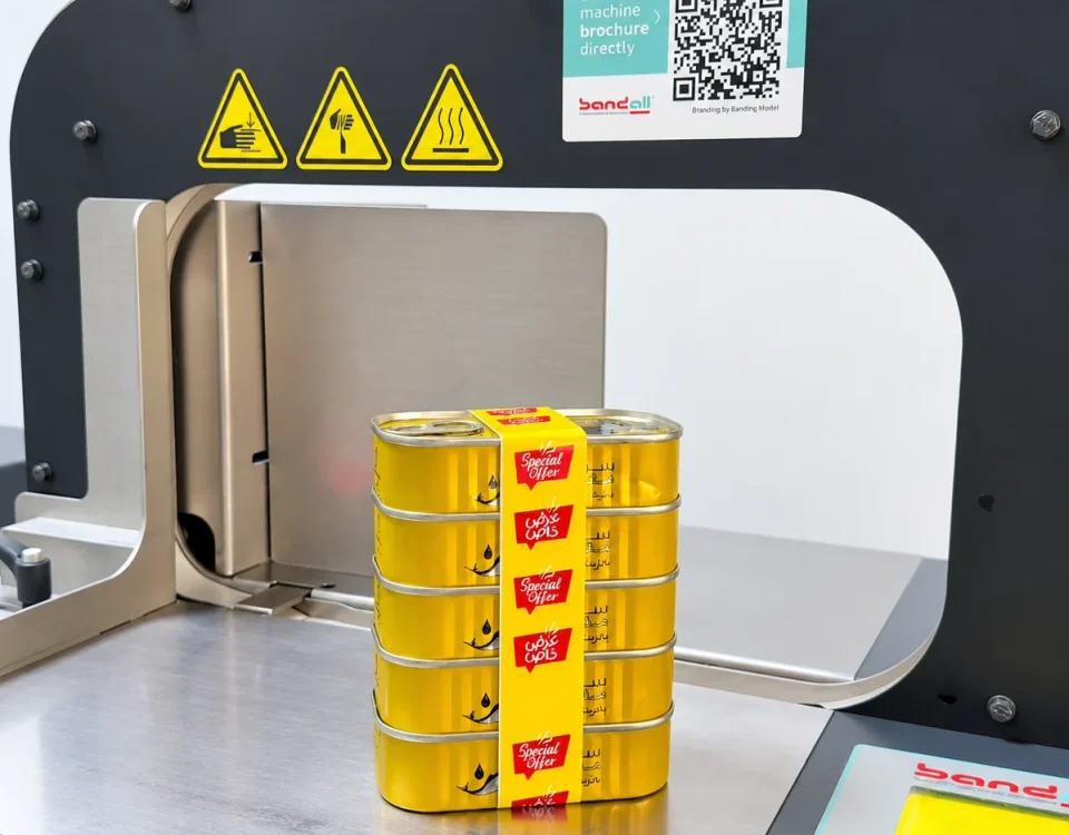 A stack of five yellow cans with a printed Special Offer band on a Bandall banding machine
